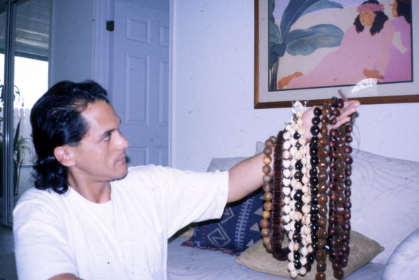 Angel Paat holding up Hawaiian necklaces he made in Orlando, Florida.