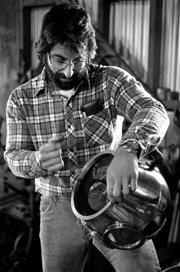 Apprentice Greek sponge diving helmet maker Nick Toth holding helmet in his grandfather's machine shop - Tarpon Springs, Florida.