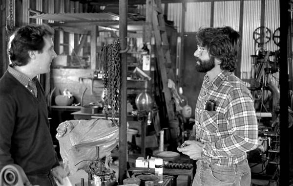 Folklorist Peter Roller listening to apprentice Greek sponge diving helmet maker Nick Toth in his grandfather's machine shop - Tarpon Springs, Florida.