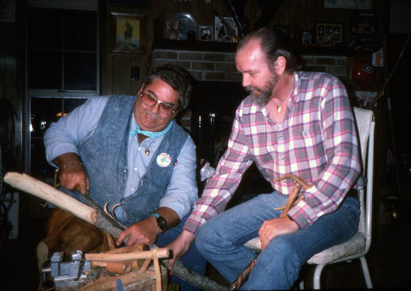 Teacher Bobby Johns (L) explaining to apprentice Randy Stewart how to strip the bark off a white oak tree