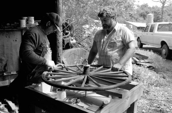 Wheelwright and coach maker John Luther and his apprentice Raymond Richardson working with a wagon wheel - McAlpin, Florida