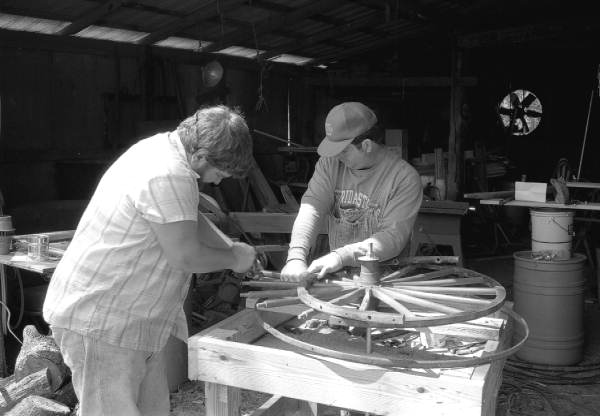 Wheelwright and coach maker John Luther and his apprentice Raymond Richardson working with a wagon wheel - McAlpin, Florida