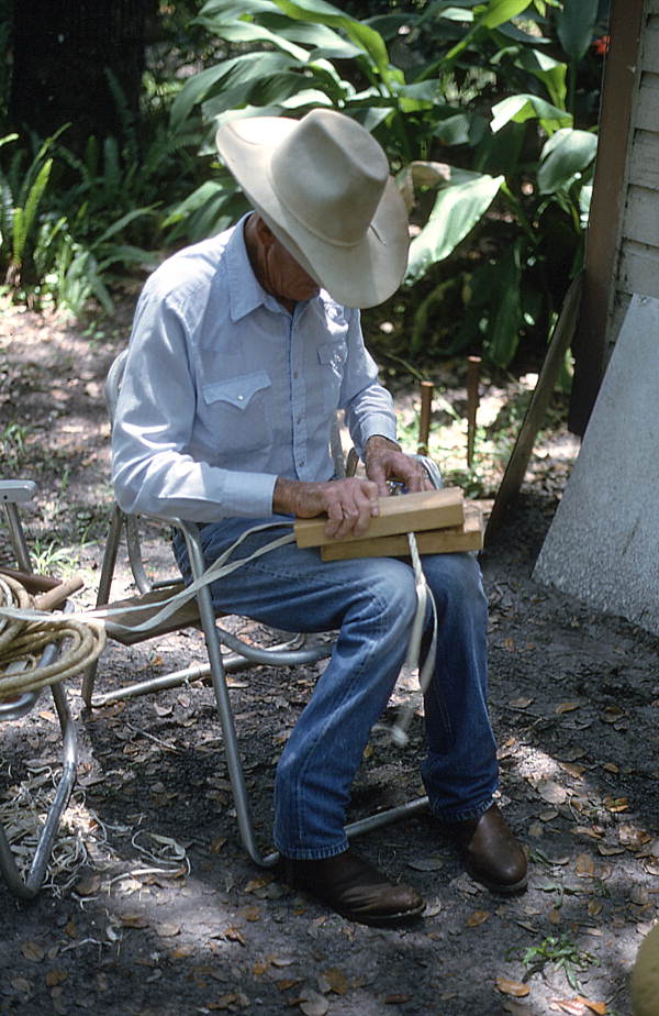 Cow whip maker George "Junior" Mills rolling a whip between blocks of wood - Okeechobee, Florida.