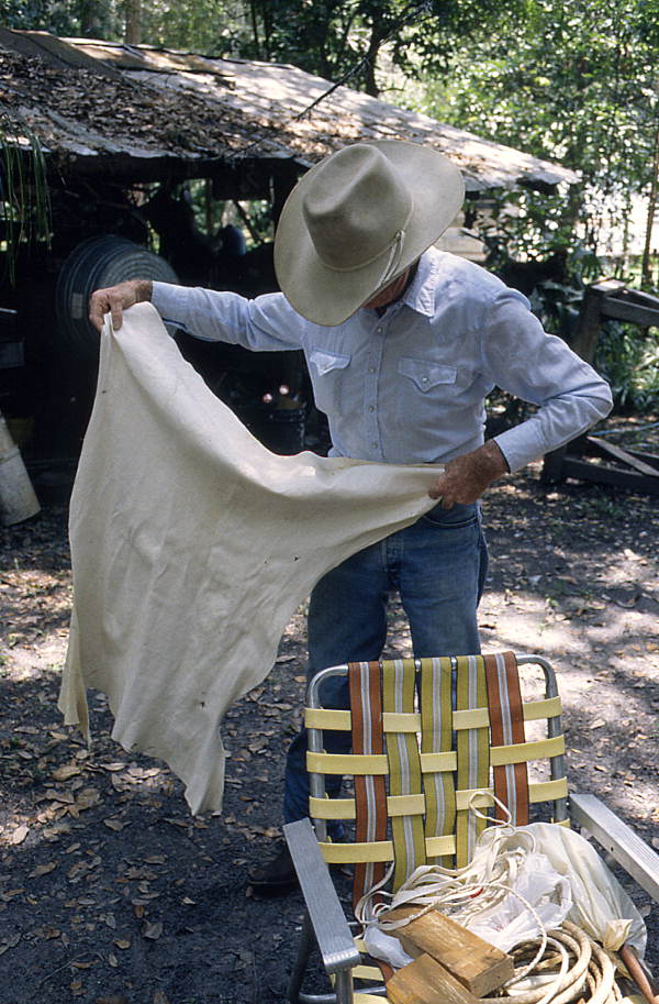 Cow whip maker George "Junior" Mills holding buckskin used for whip braiding - Okeechobee, Florida.