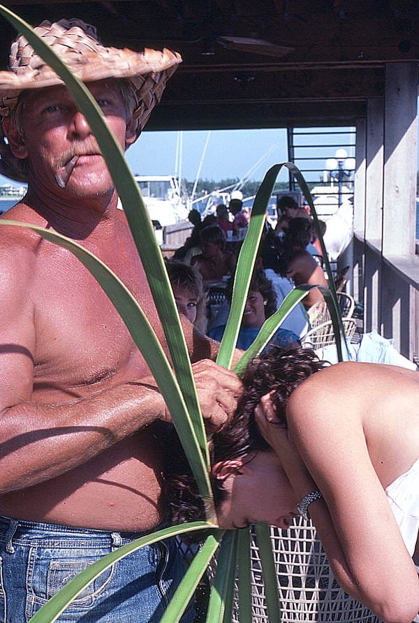 Palm frond hat maker Vic Simmons sizing hat to customer's head - Boynton Beach, Florida.