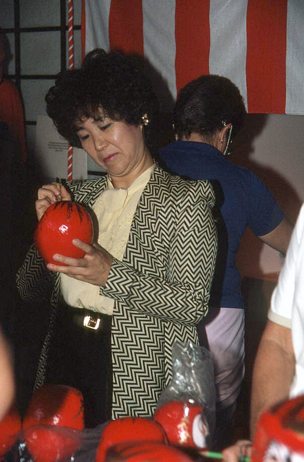 Woman painting daruma doll at Japanese New Years celebration - Delray Beach, Florida.
