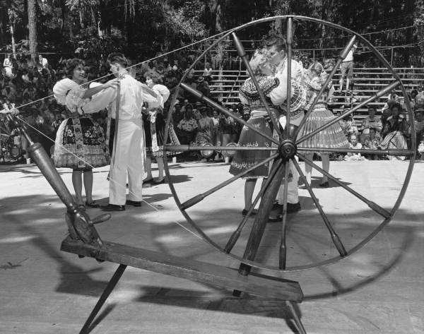Beseda dancers performing next to a spinning wheel at the Florida Folk Festival - White Springs, Florida