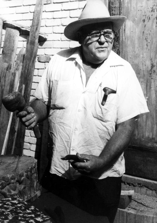 Wood-carver John Albert holding a mallet and chisel he uses to carve wood- Tampa, Florida.