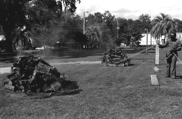 Unidentified man controlling fires for a mullet fish smoke - Monticello, Florida