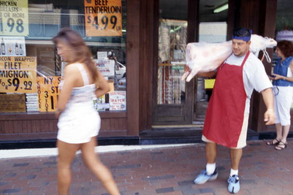 Butcher carries lamb meat for a customer - Tarpon Springs, Florida.