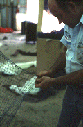 Net maker Billy Burbank II beginning repair of a torn fishing net - Fernandina Beach, Florida