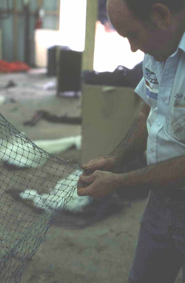 Net maker Billy Burbank II beginning repair of a torn fishing net - Fernandina Beach, Florida