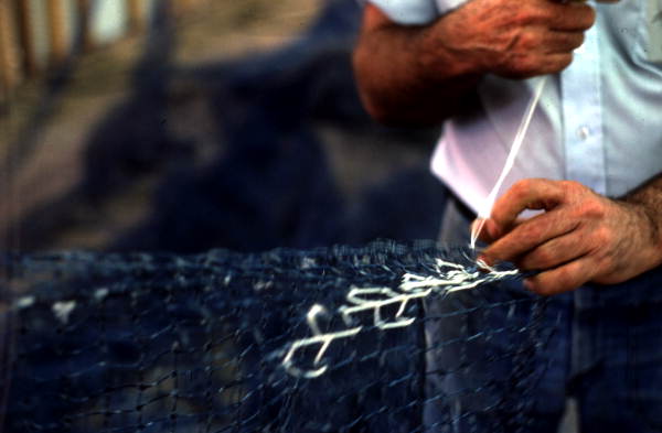 Net maker in the process of repairing a fishing net - Fernandina Beach, Florida