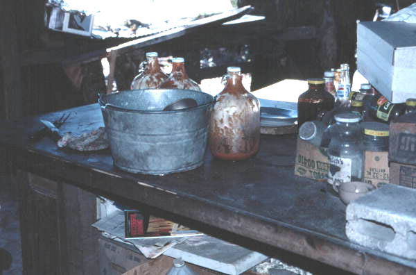 Table holding bucket with water for basting and jars of barbecue sauce mixture - Lake City, Florida.