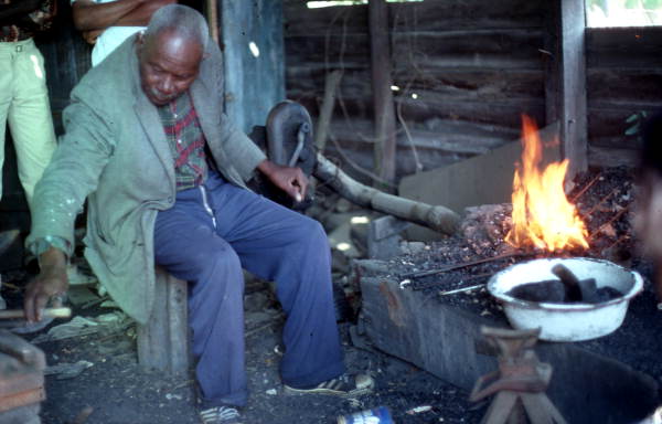 Blacksmith Thomas Rains at work while others look on - Jefferson County, Florida