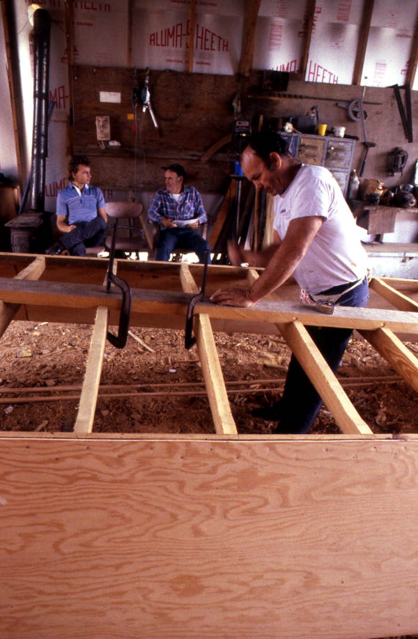 Bobby Shiver building an oyster skiff while two men watch - Eastpoint, Florida