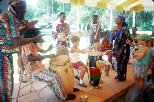 Konbo Guinyn band showing child how to play drums during the 1990 Florida Folk Festival - White Springs, Florida