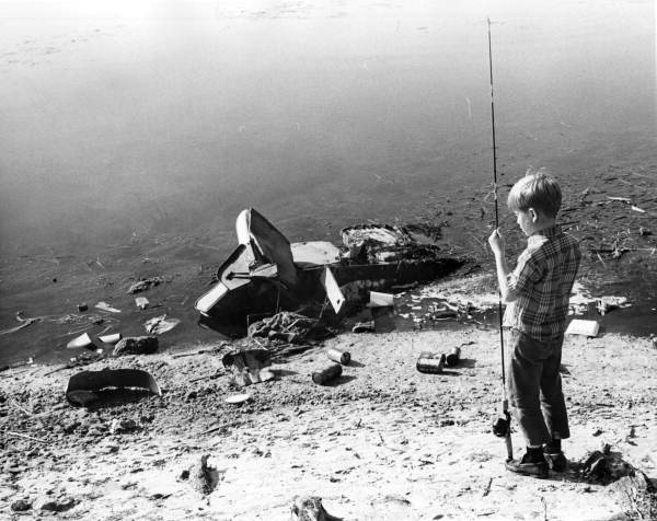 Unidentified boy looks at garbage on the shore