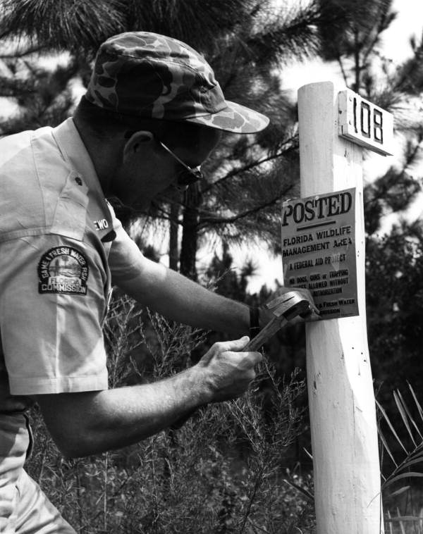 Wildlife officer William "Bill" Tiller posting a sign in Bay County, Florida.