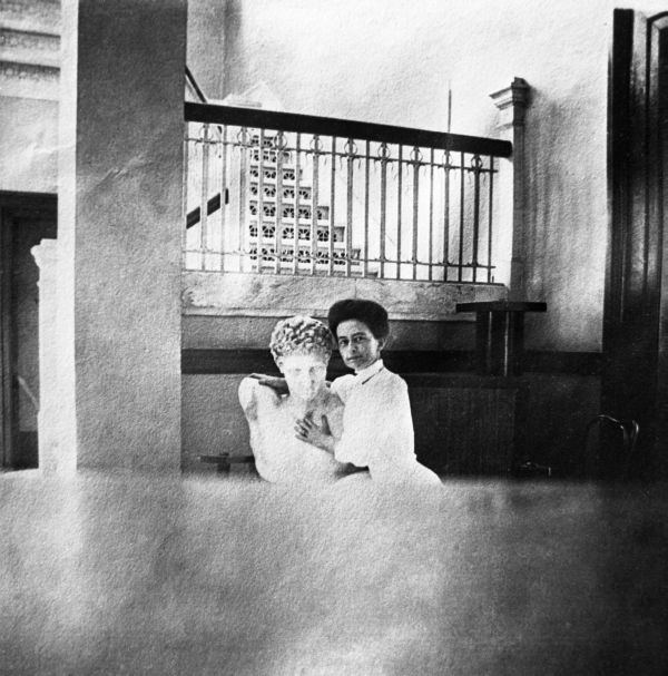 Staff member holding bust in front of interior staircase.