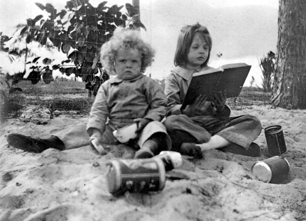 Virginia Ahern reading a book while her brother plays in the dirt - Babson Park, Florida