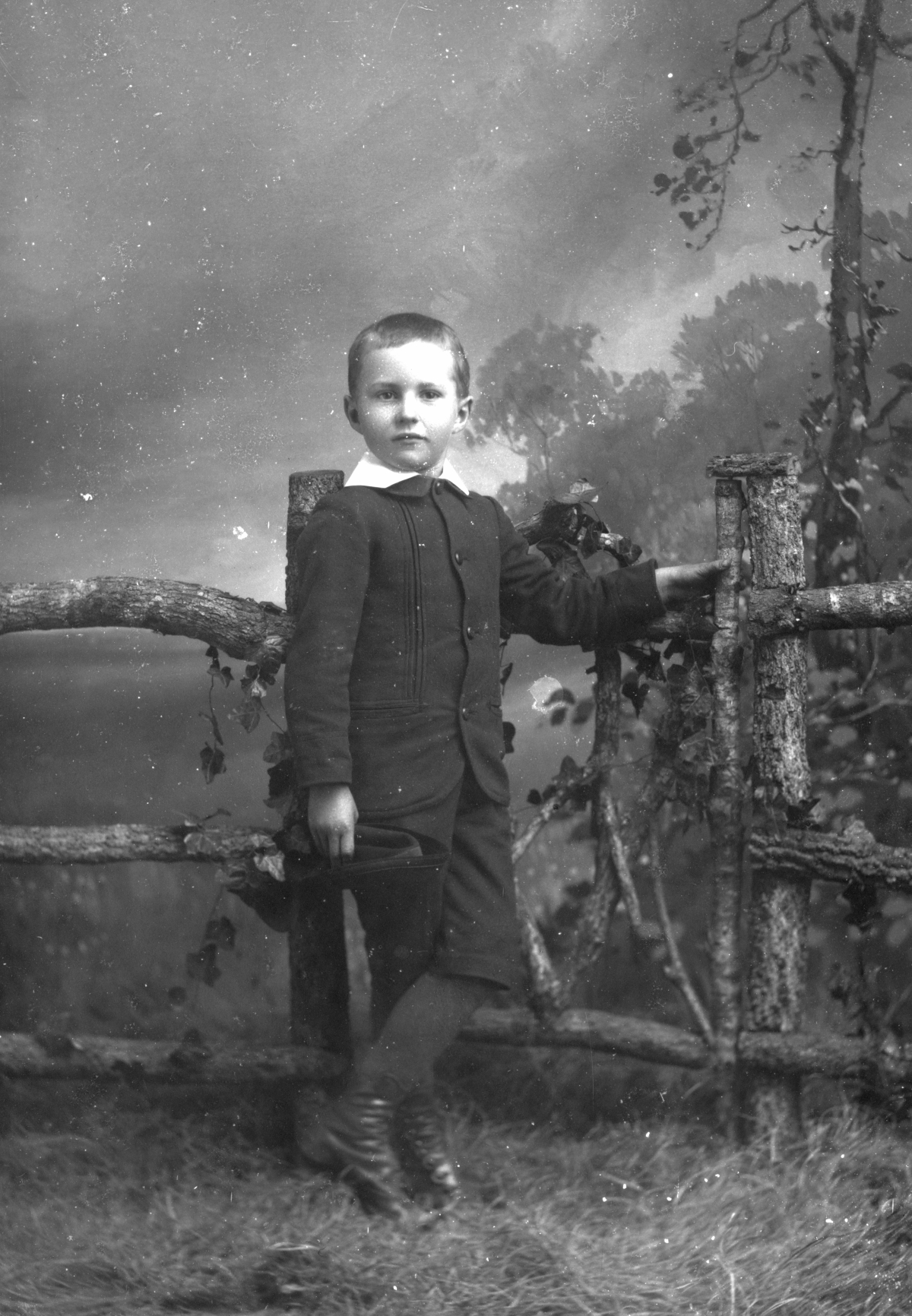 Boy at the gate with hat in hand.