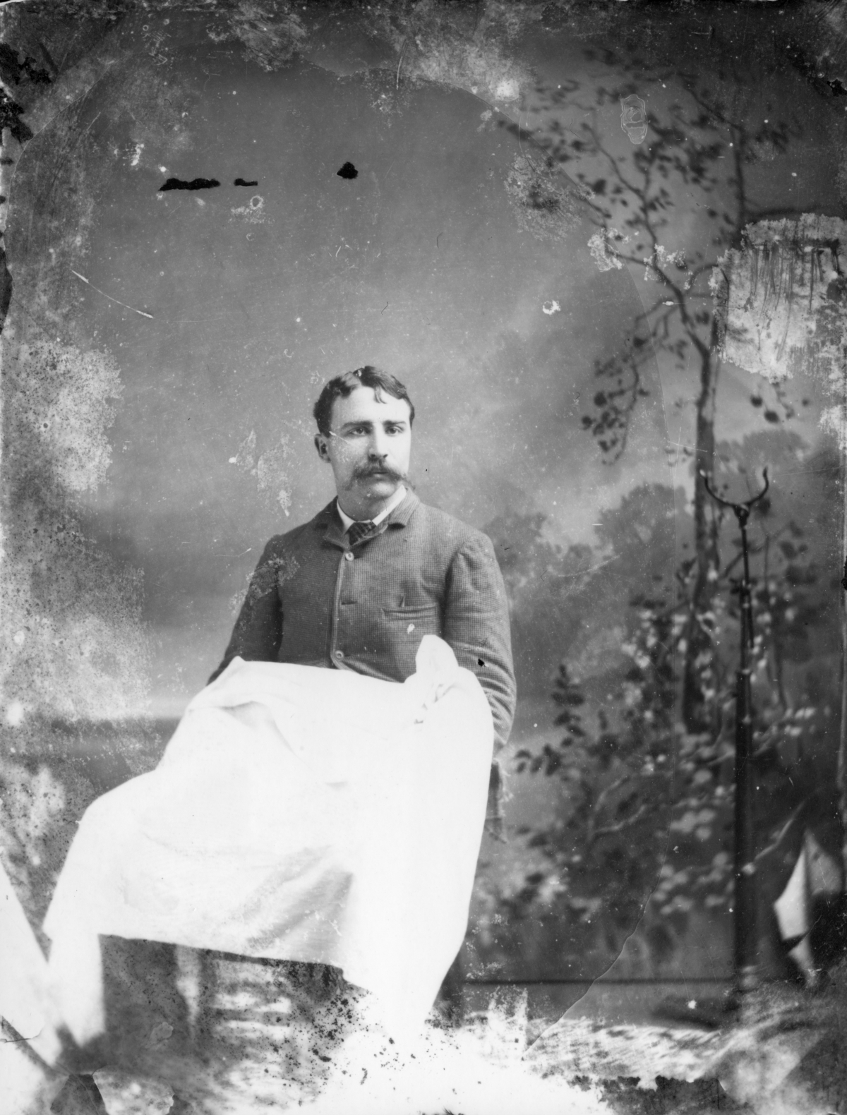 Seated man with a cloth covering his lap.