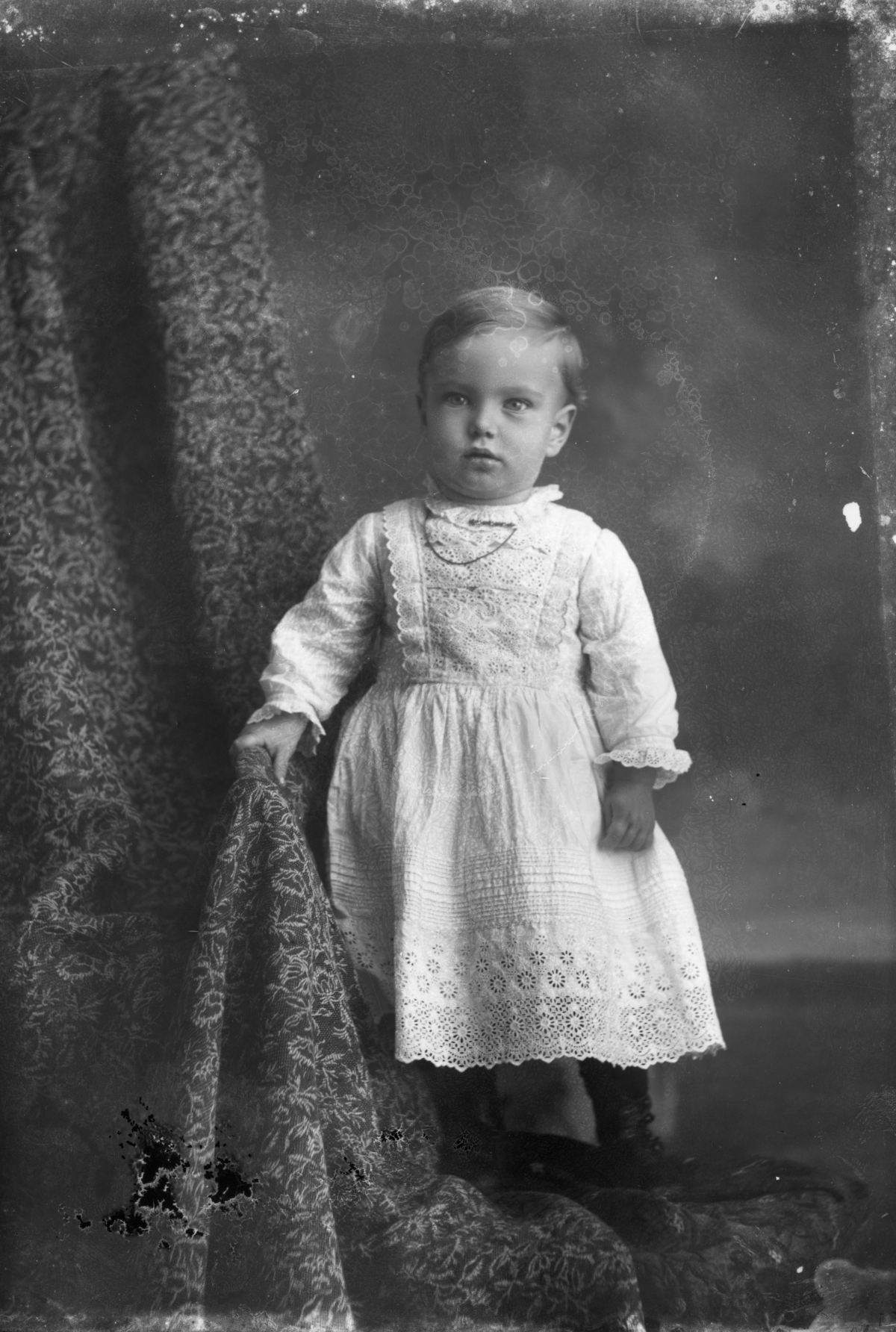 Child standing in white dress.