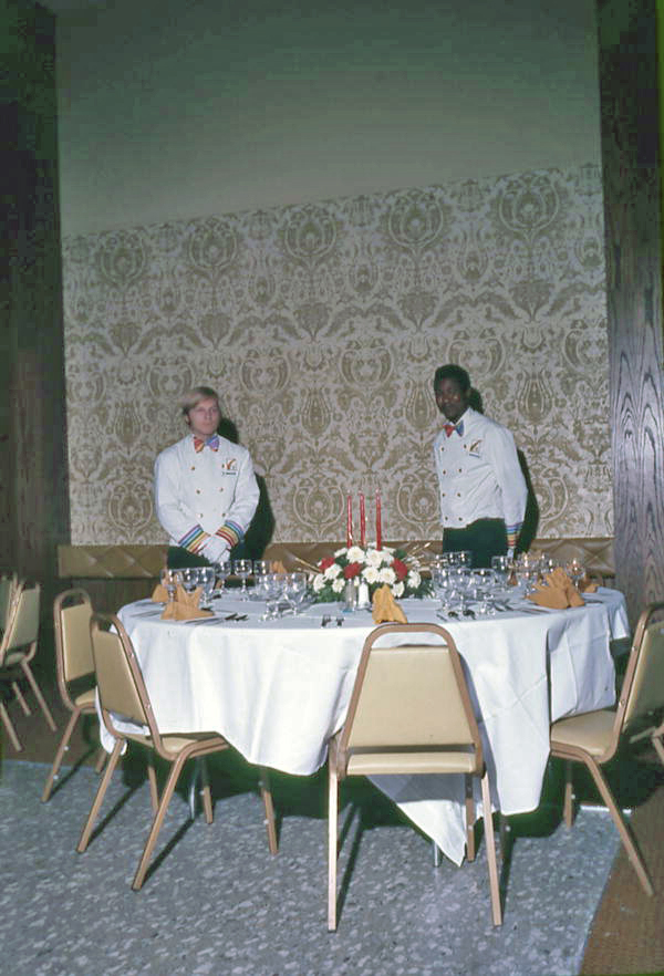 Employees standing by a dining table inside the Hilton Hotel - Tallahassee, Florida.