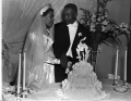 Newly married African American couple cutting cake
