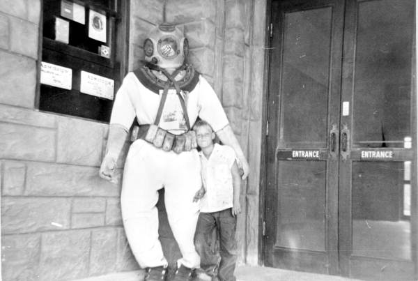 Art McKee's son, Mick, posing next to dive suit at his father's museum - Plantation Key, Florida
