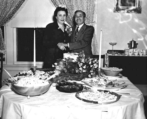 Celia and Joe Meltzer standing behind a table full of food