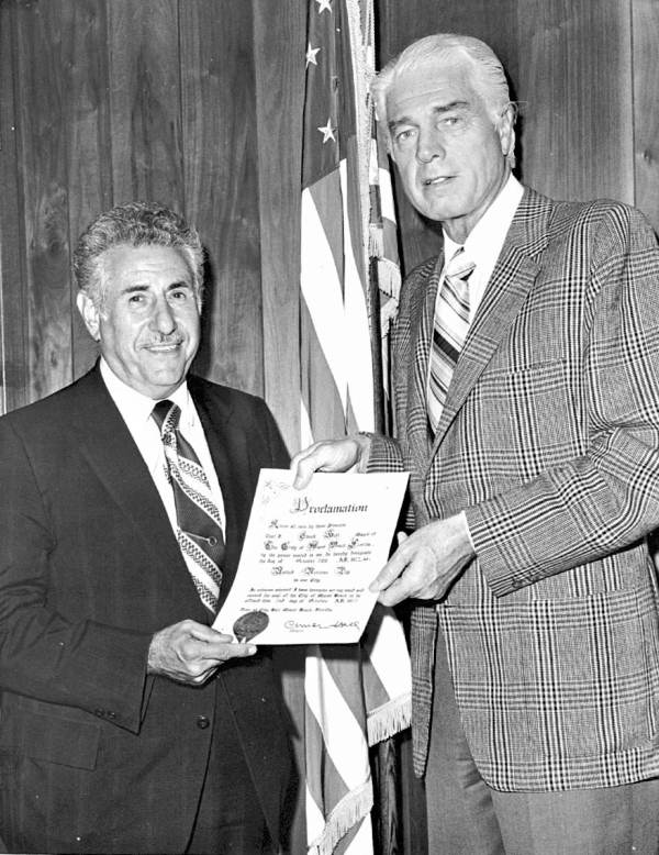 Andre Bialolenki holding proclamation with Miami Beach mayor.