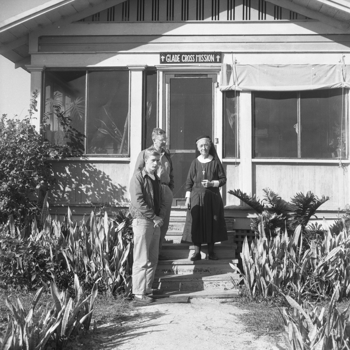Deaconess Harriet Bedell, Dr. Georg Neumann, and Holm Neumann standing in front of the Glade Cross Mission