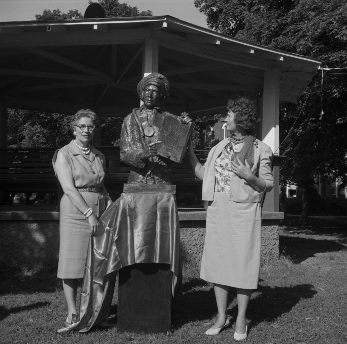 Two women standing by a statue