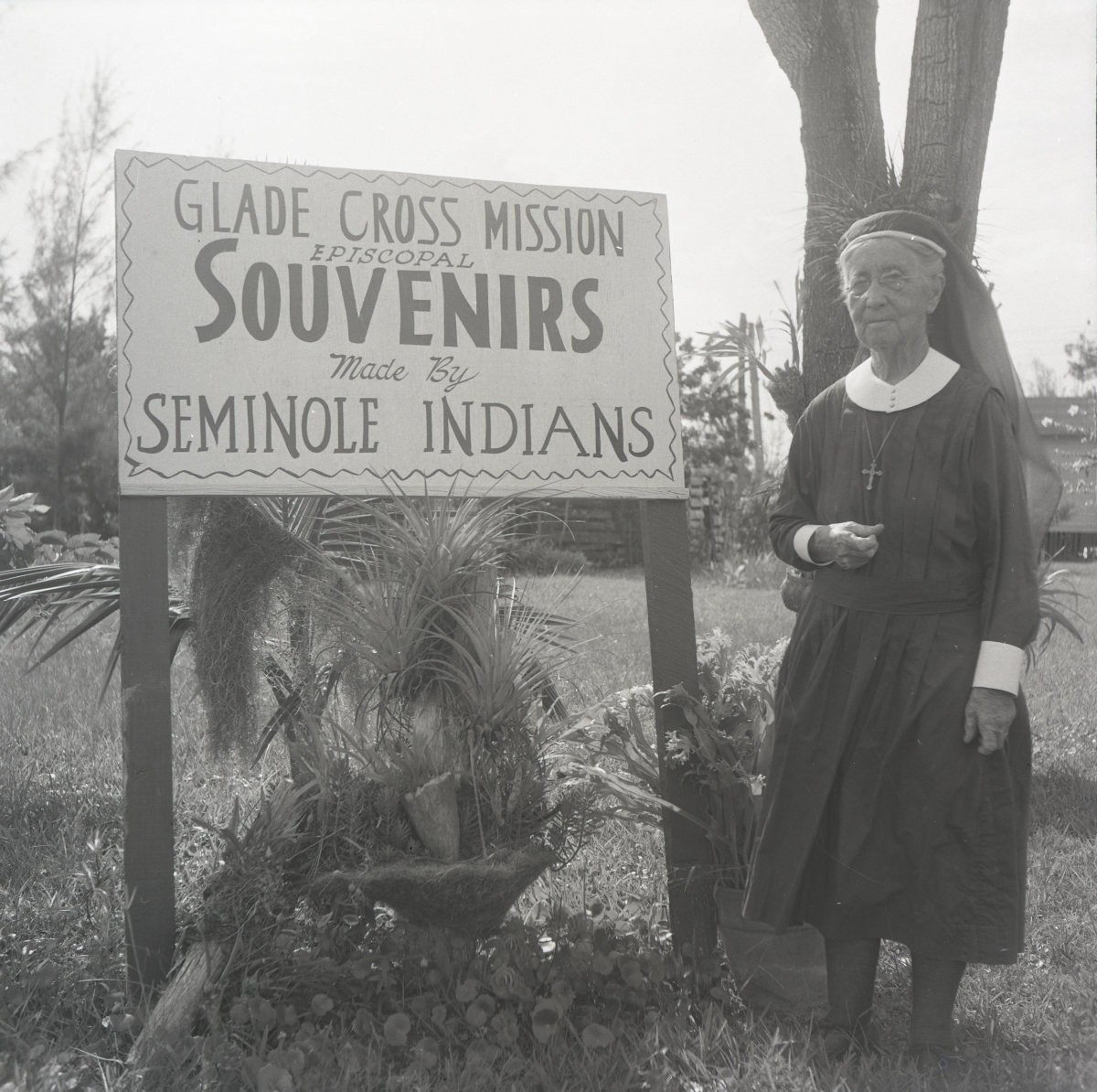 Deaconess Harriet Bedell standing in front of the Glade Cross Mission sign