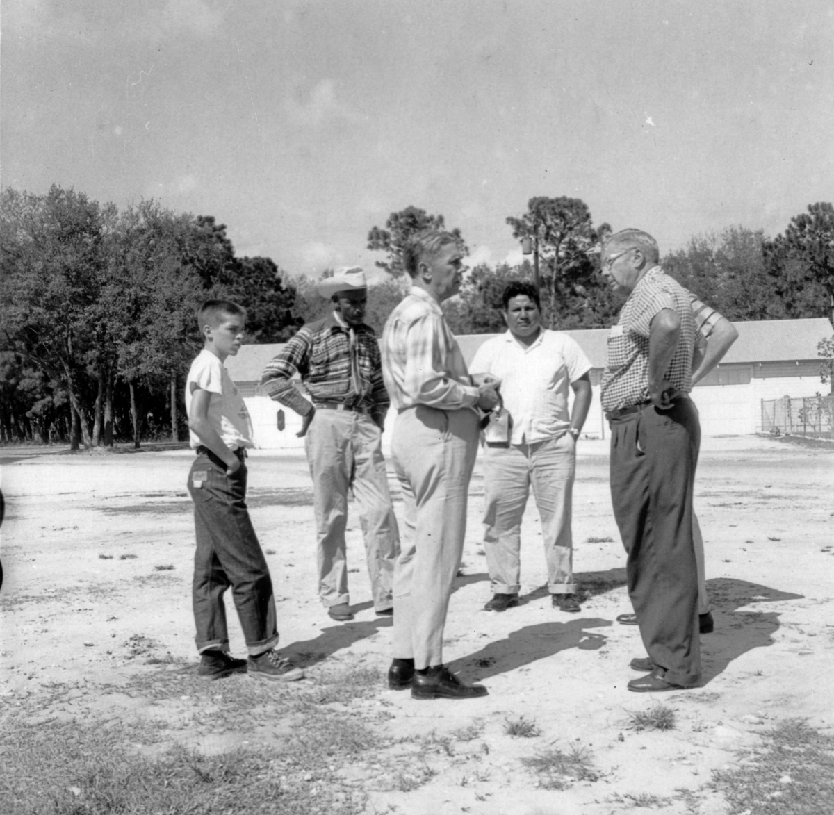 Young boy standing with four men in an open area