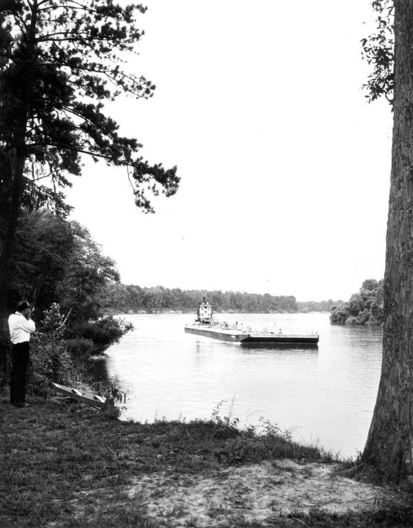 Man at Torreya State Park photographing a barge on the Apalachicola River
