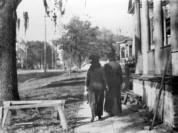 Two people walking along a sidewalk in Tallahassee.