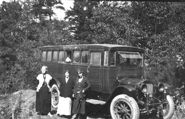 Women standing next to an antique car