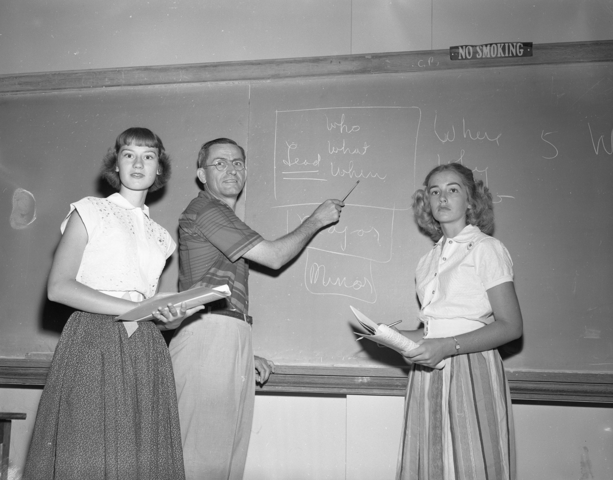Students and teacher working on a blackboard.