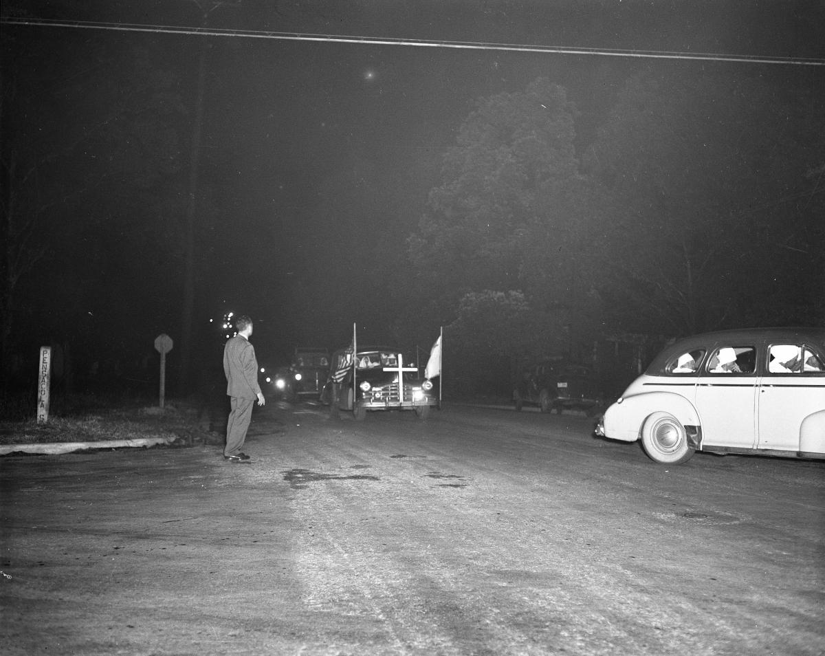 Ku Klux Klansmen in costume, riding in automobiles