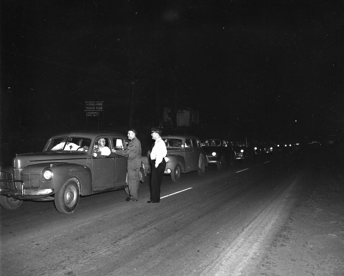 Ku Klux Klan in their cars and talking with men standing in the road