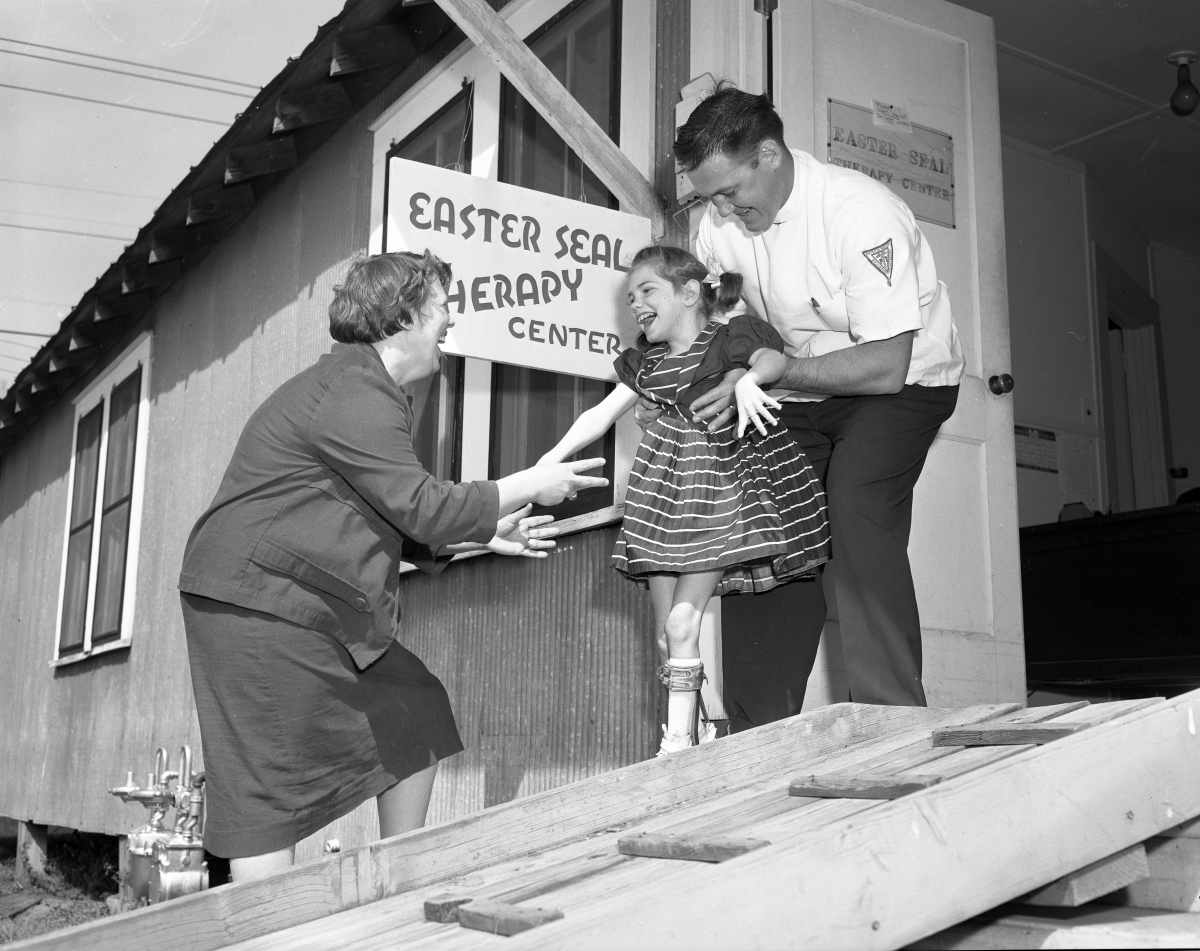 Therapist helping a patient walk down a ramp at the Easter Seal therapy center.
