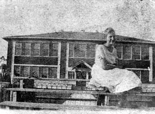 Edwina Parkinson seated on a fence at an Alva school