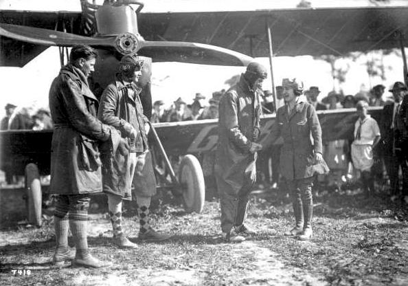 Mabel Cody and three aviators from her "Flying Circus" in front of a biplane in Coral Gables.