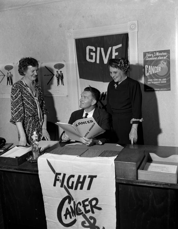 Campaign chairman Joe Walsh from the Duval County Chapter of the American Cancer Society looking at book with unidentified women - Jacksonville, Florida
