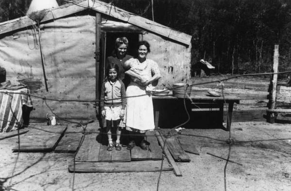 Family members in front of their tarpaper home.