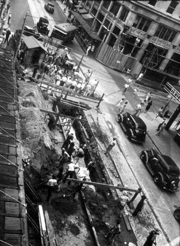 Men working on sewer pipe under street.