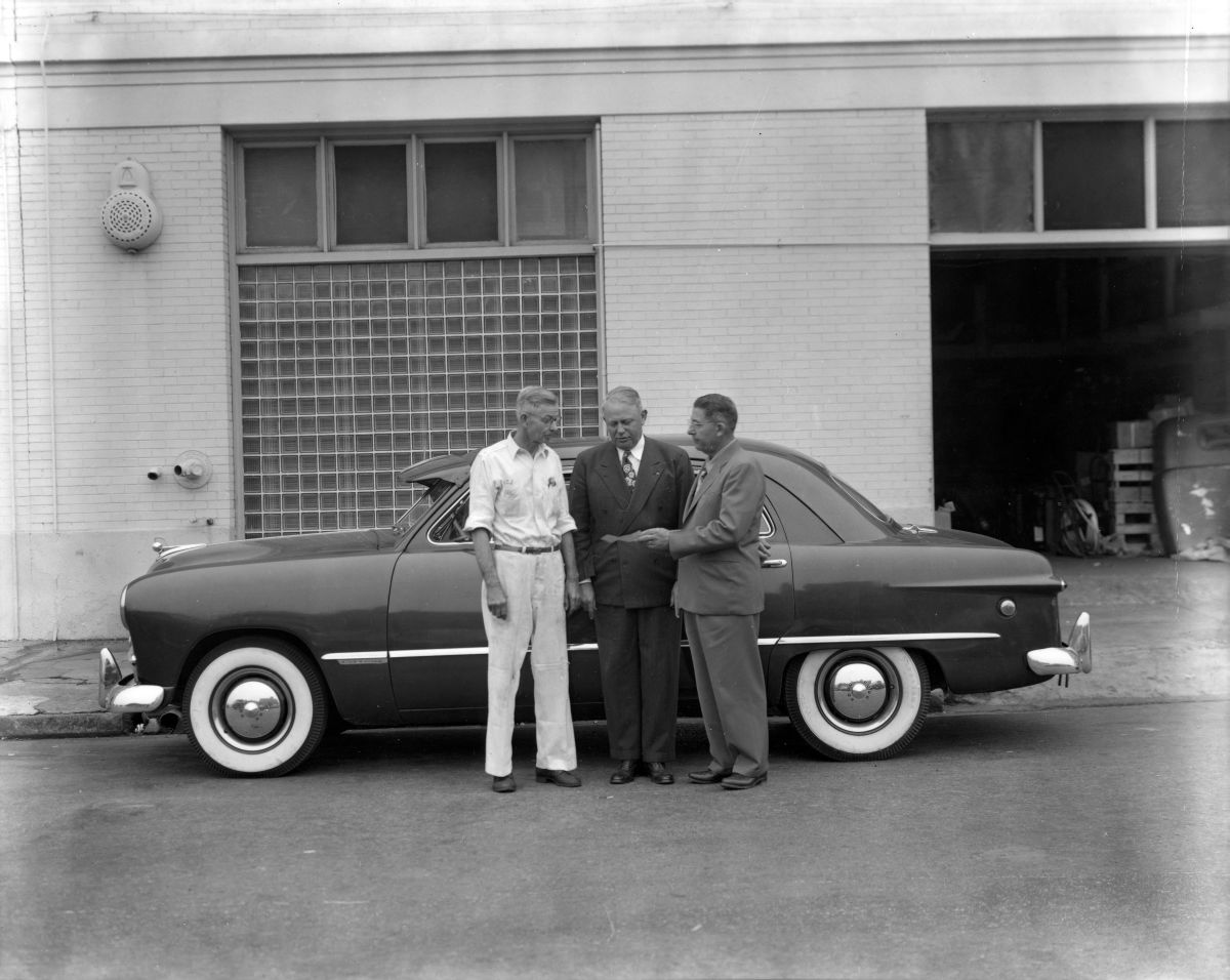 Men standing with a car.